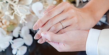 画像：結婚指輪をつけた手を握り合う